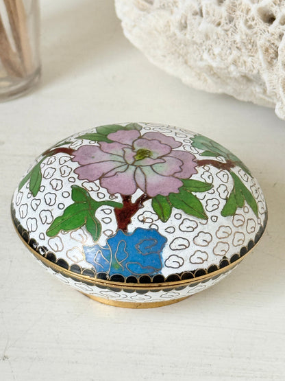 Vintage brass and enamel cloisonne trinket box with floral lid and turquoise interior photographed on a white surface