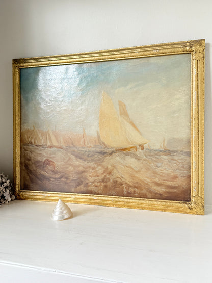 A framed oil painting of a sailing yacht on choppy water, housed in an ornate gold frame and displayed on a white mantelpiece.