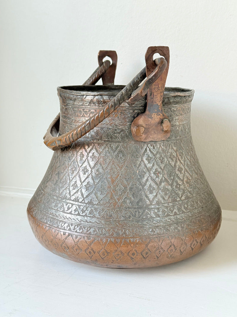 antique Middle Eastern water ewer with engraved diamond and foliate pattern and copper base, displayed on white surface