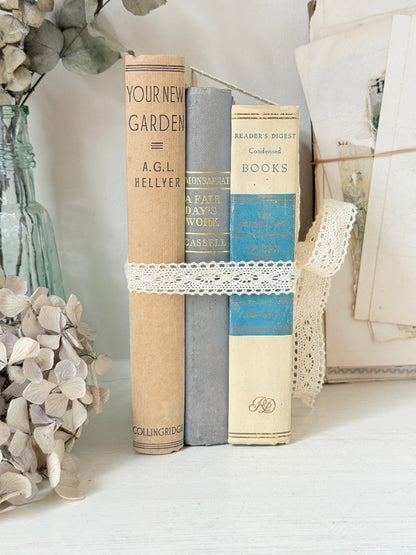 Bundle of vintage cream and blue cloth books with one patterned cover tied with ivory lace for shelf styling