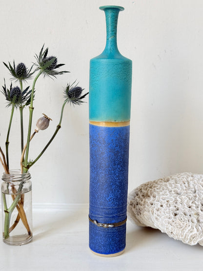 Tall vintage studio pottery bottle vase in turquoise and cobalt blue glaze, photographed on a white surface
