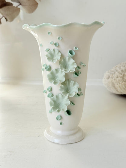 White Chessell Pottery studio vase with rippled rim and raised aqua floral decoration photographed on a white surface