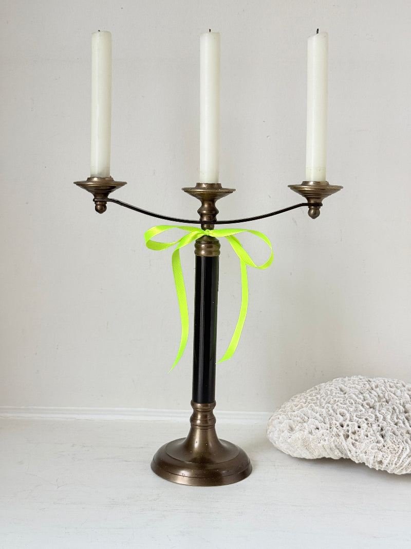 Vintage three arm candelabra in brass and ebonised metal with ivory taper candles styled on a white surface