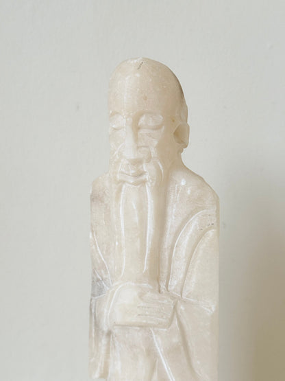 vintage alabaster gentleman figure on square base with carved detail, photographed on white surface with hydrangea flowers.