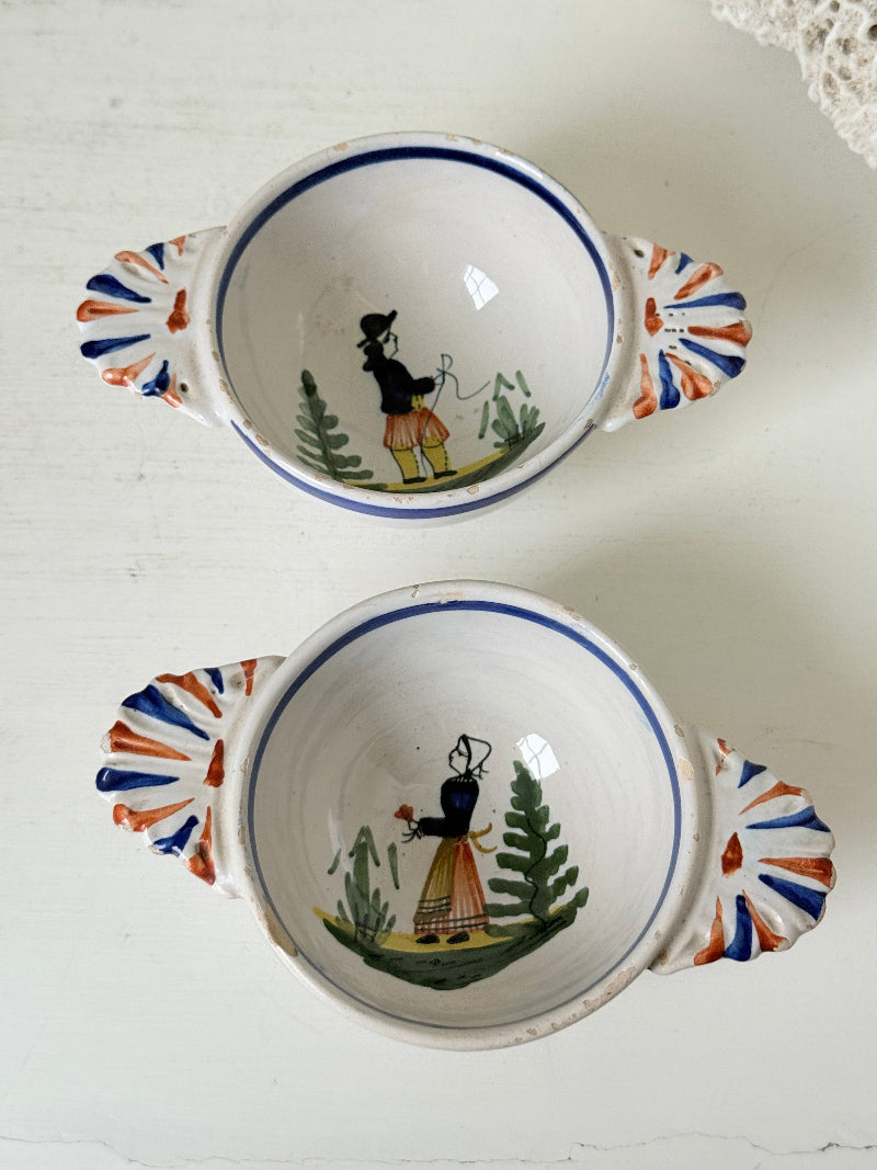Pair of vintage French Quimper olive bowls with Breton figure and fan handles, photographed on a white surface