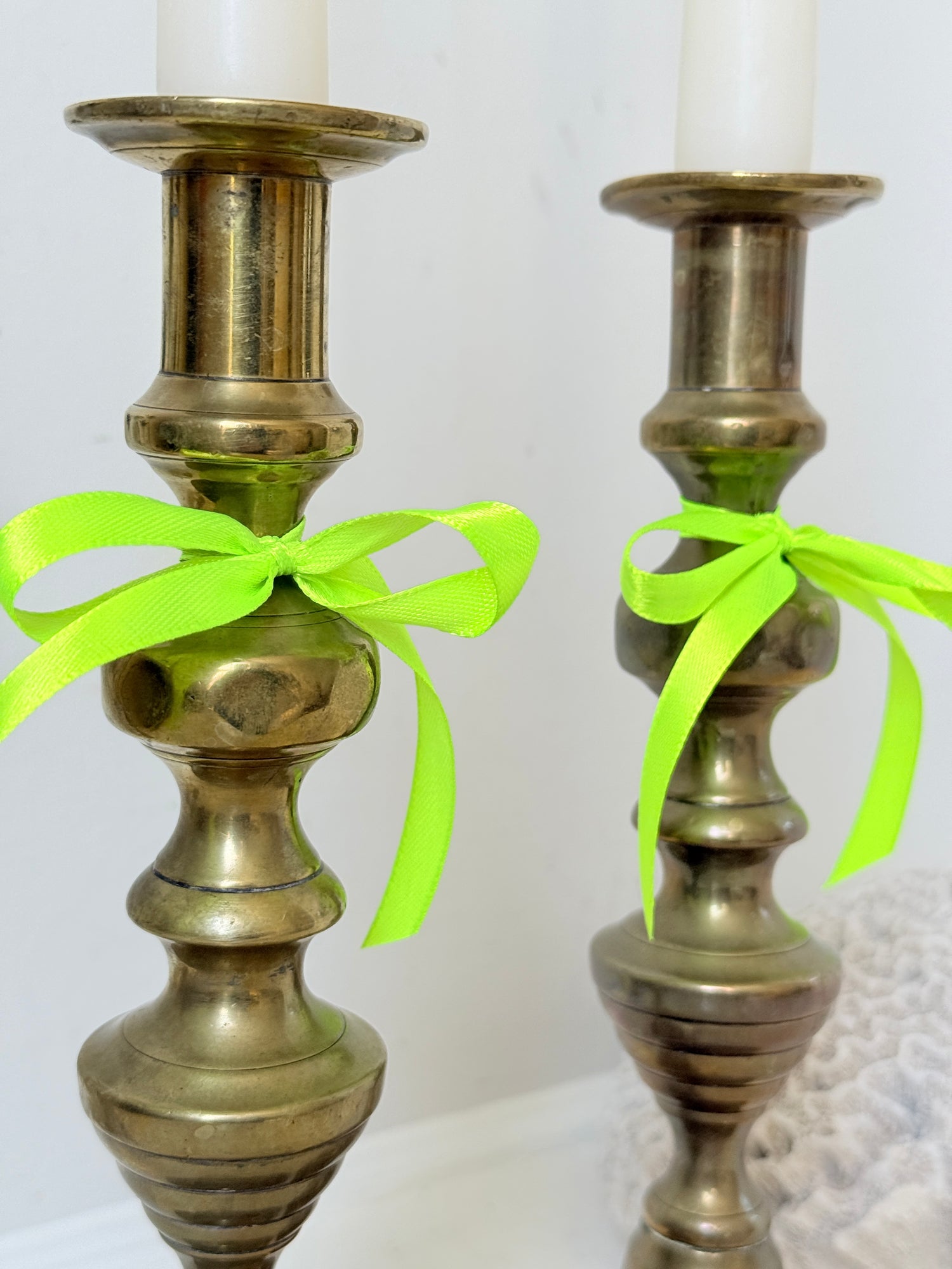 Pair of vintage brass candlesticks with turned stems and square bases, photographed on a white surface