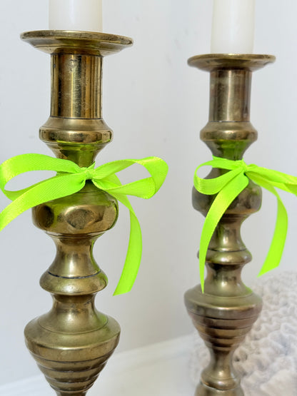 Pair of vintage brass candlesticks with turned stems and square bases, photographed on a white surface