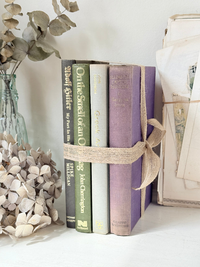 Bundle of vintage books with a heather purple cloth cover over green and cream spines tied with natural twine