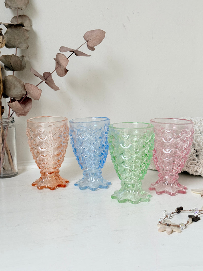 Set of 4 vintage pastel pressed glass mermaid goblets with textured scale pattern on a white surface