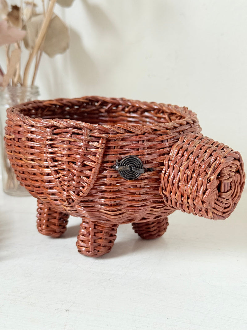 Vintage wicker pig basket planter in warm brown, photographed on a white surface