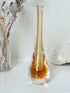 Amber and clear 1960s glass vase with narrow neck and rounded base, photographed on a white surface with dried stems.