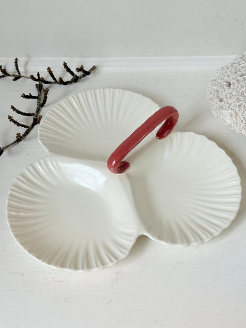 Poole Pottery double scallop hors d’oeuvre dish in white glaze with red handle photographed on a white surface