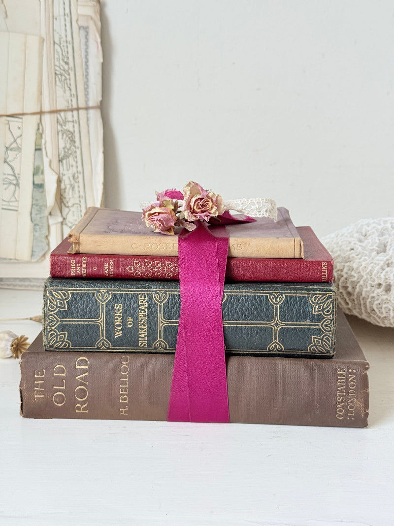 Vintage decorative book bundle with pink ribbon, dried flower detail and aged hardback covers for shelf and table styling