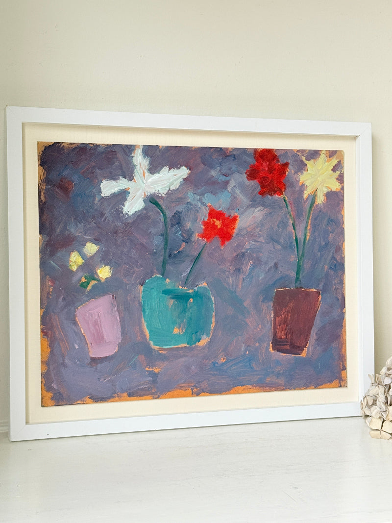 A framed painting of three colorful flower vases against a textured purple and blue background, displayed on a white surface against a beige wall.