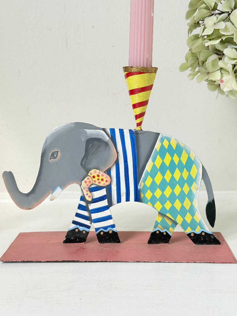 Hand painted metal elephant candlestick in circus-style decoration with colourful patterns, photographed on a white surface
