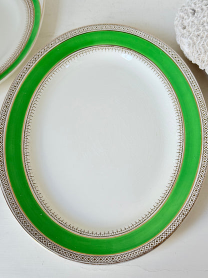 Pair of vintage oval serving platters with bright green Art Deco style border photographed on a white surface