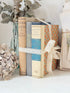 Bundle of vintage cream and blue cloth books with one patterned cover tied with ivory lace for shelf styling