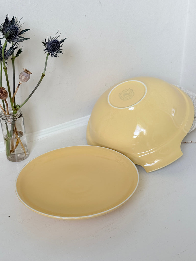 Vintage Poole Pottery lidded serving dish in soft yellow glaze with side handles, photographed on a white surface