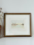 Framed vintage print of Poole Quay harbour scene in muted tones, under glass with gilt and wood-effect frame, on white surface.