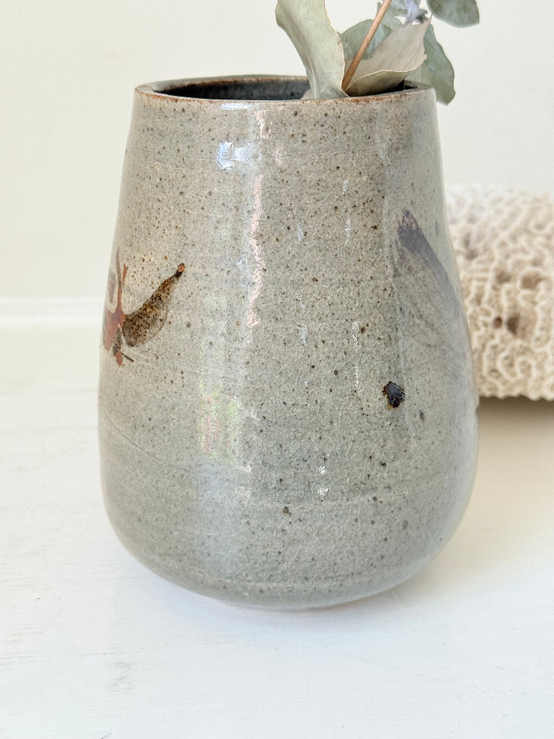 Hand thrown studio pottery vase with ash glaze and brushstroke motif, photographed on white surface