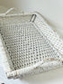 Vintage white painted wicker tray with woven handles photographed on a white surface