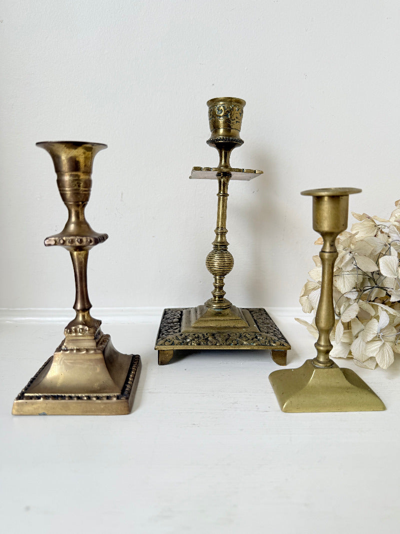 vintage brass trio of candlesticks in mixed designs photographed on white surface
