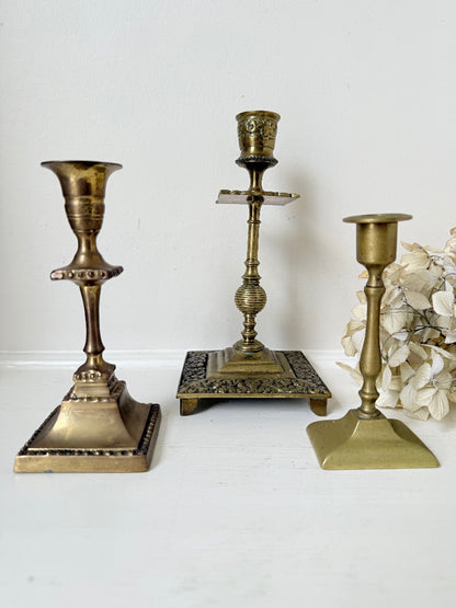 vintage brass trio of candlesticks in mixed designs photographed on white surface