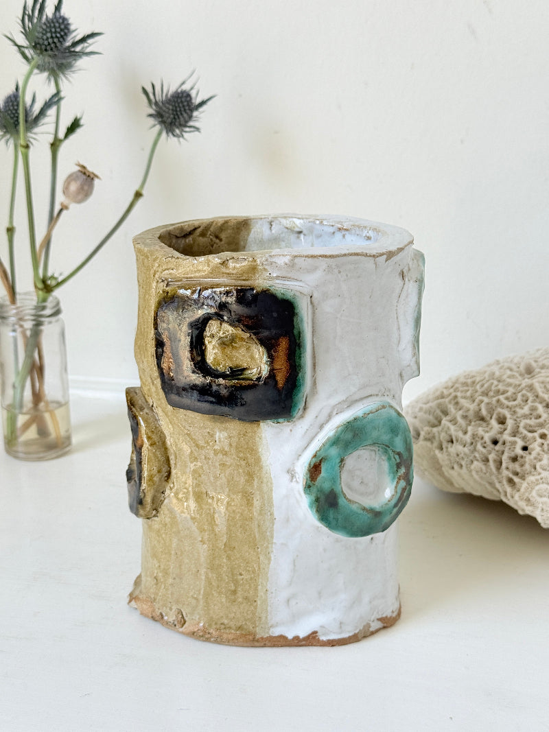 Vintage studio pottery vase in white, ochre and turquoise with abstract applied decoration, photographed on a white surface