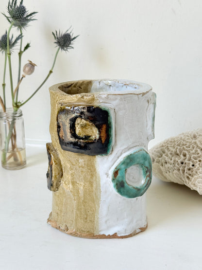 Vintage studio pottery vase in white, ochre and turquoise with abstract applied decoration, photographed on a white surface