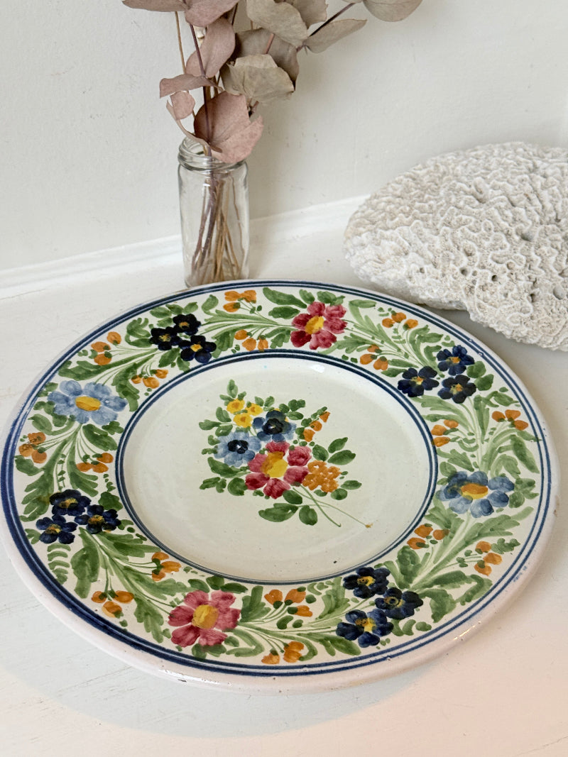 Vintage Italian majolica floral plate with blue green yellow and pink decoration photographed on a white surface