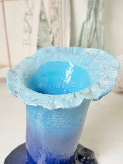 Handmade studio pottery trumpet vase in ombre blue with a frilled rim, photographed on a white surface