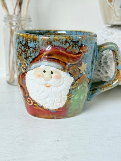 Pair of Christmas mugs with Santa and snowman designs photographed on a white surface.
