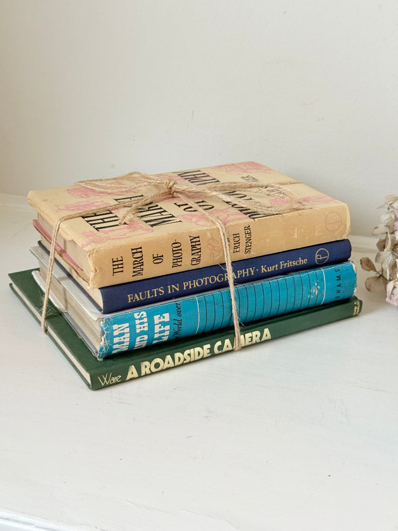 Bundle of vintage books in blue and neutral tones tied with twine, photographed on a white surface