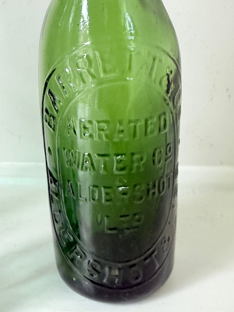 Trio of antique aqua and green glass bottles with embossed lettering, photographed on a white surface