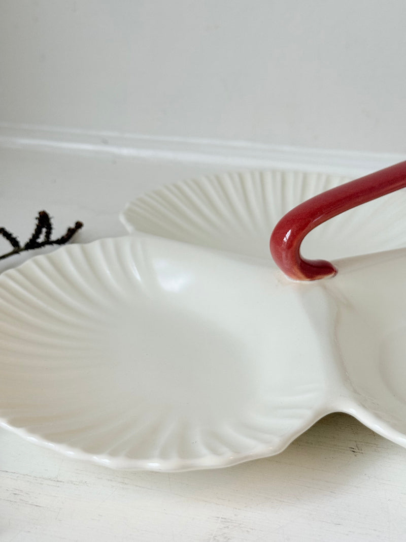 Poole Pottery double scallop hors d’oeuvre dish in white glaze with red handle photographed on a white surface