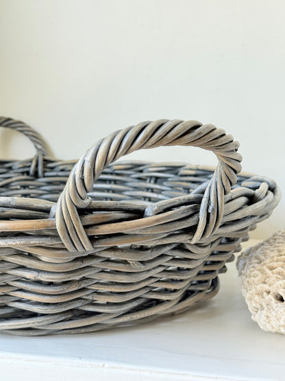 Large vintage woven basket with handles, photographed on a white surface