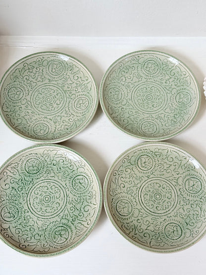 Set of four Thai celadon side plates with embossed patterns and sage green crackled glaze, stacked and photographed on white surface