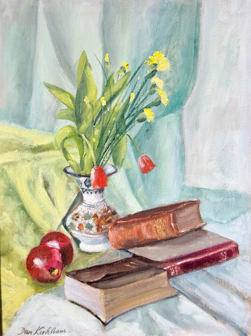 A still life oil painting depicting a white patterned vase filled with green leaves and yellow flowers, set next to two red apples and a stack of vintage brown books on draped light blue and green fabric.