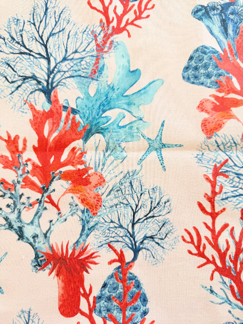 The Blue Loft coral reef cotton tea towels in turquoise and pale pink with coastal marine pattern photographed on a stone surface.