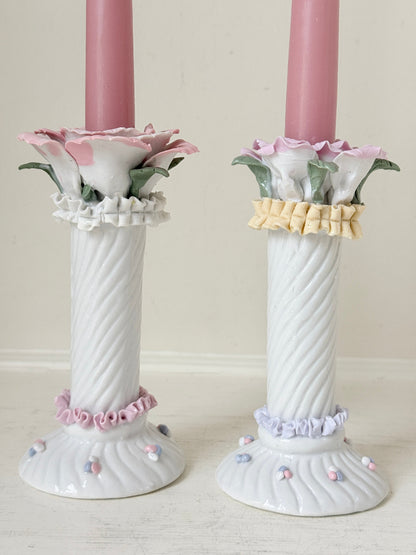 Pair of vintage floral ceramic candlesticks with rose candle cups and pink taper candles styled on a white surface