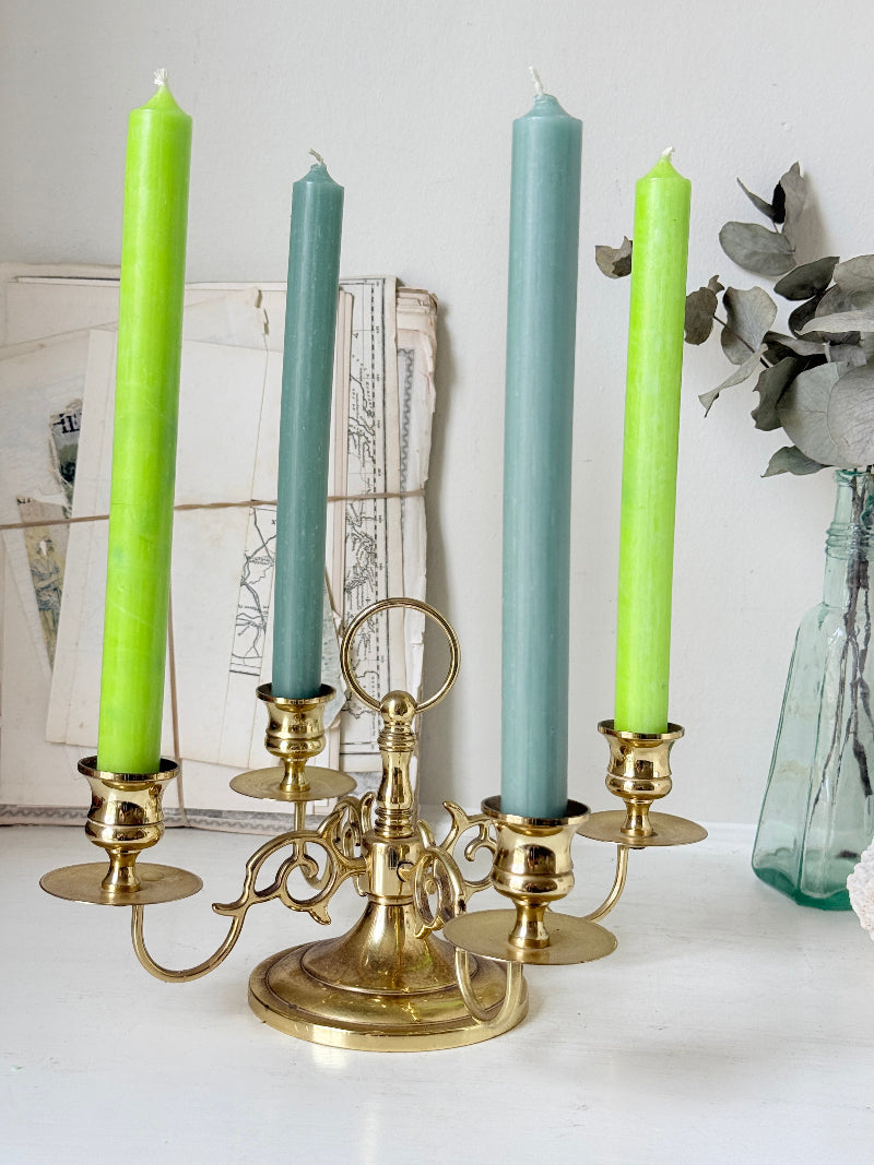 Brass five light candelabra with scrolled arms and a central ring handle on a domed base, photographed on a white surface