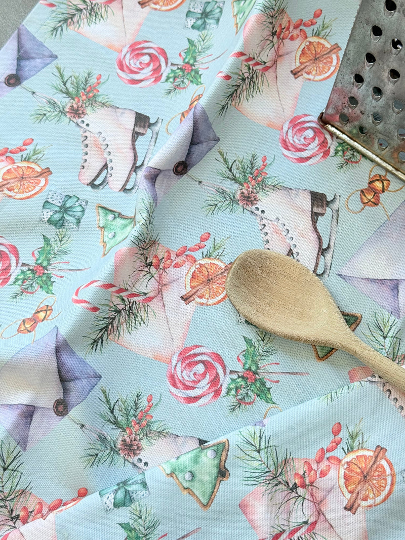 Blue Loft Christmas cotton tea towel with ice skate and candy pattern photographed on a white surface.