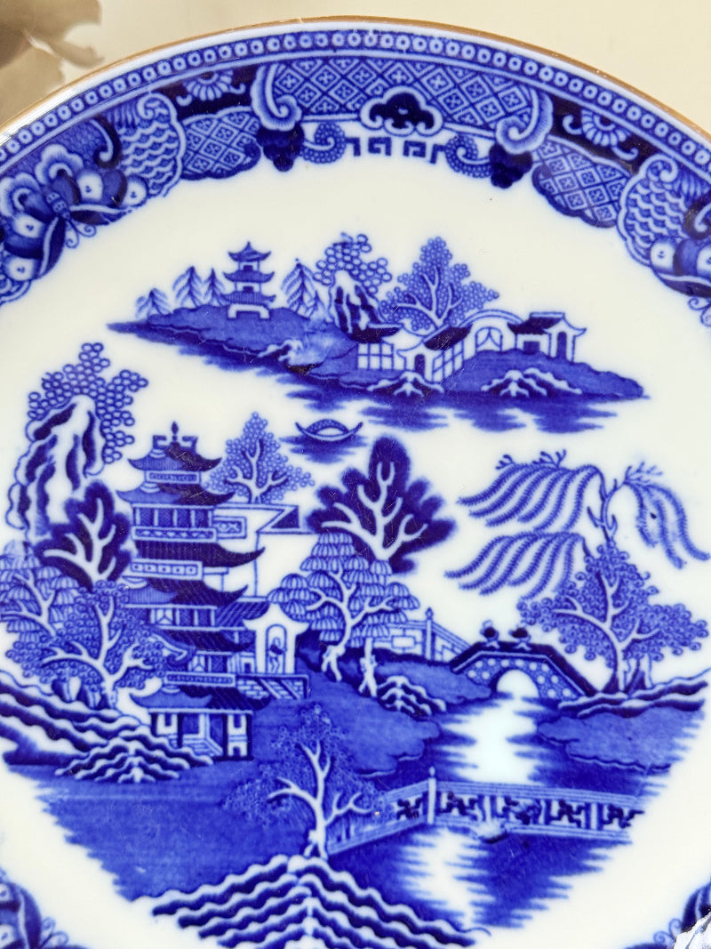 Antique Blue Willow serving plate with twin handles shown on a white surface.