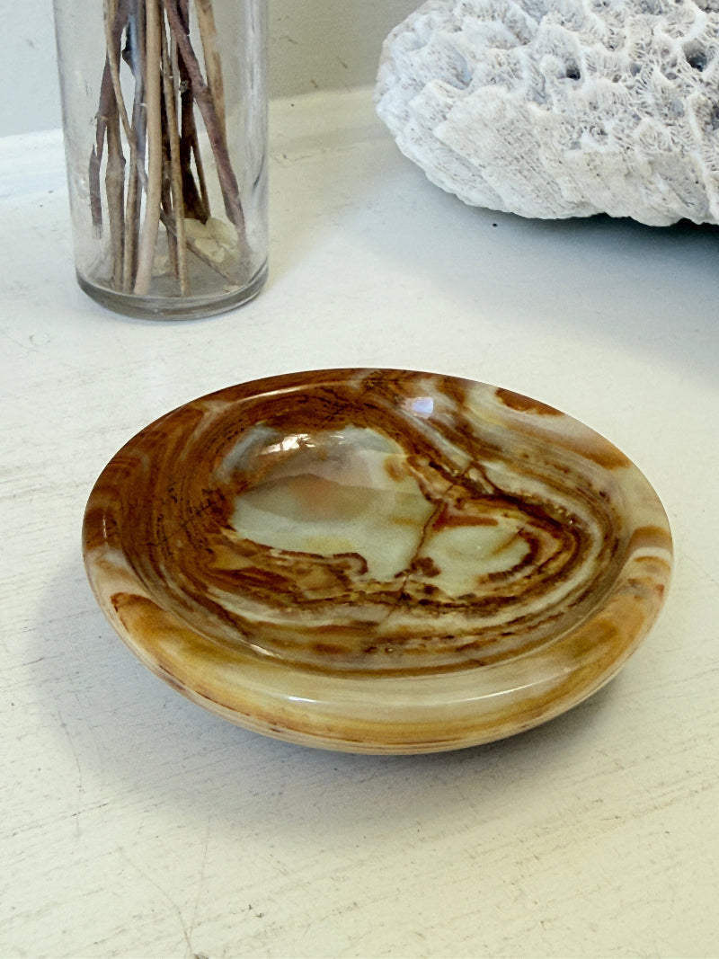 Vintage onyx marble soap dish in honey and cream with banded veining, photographed on a white surface