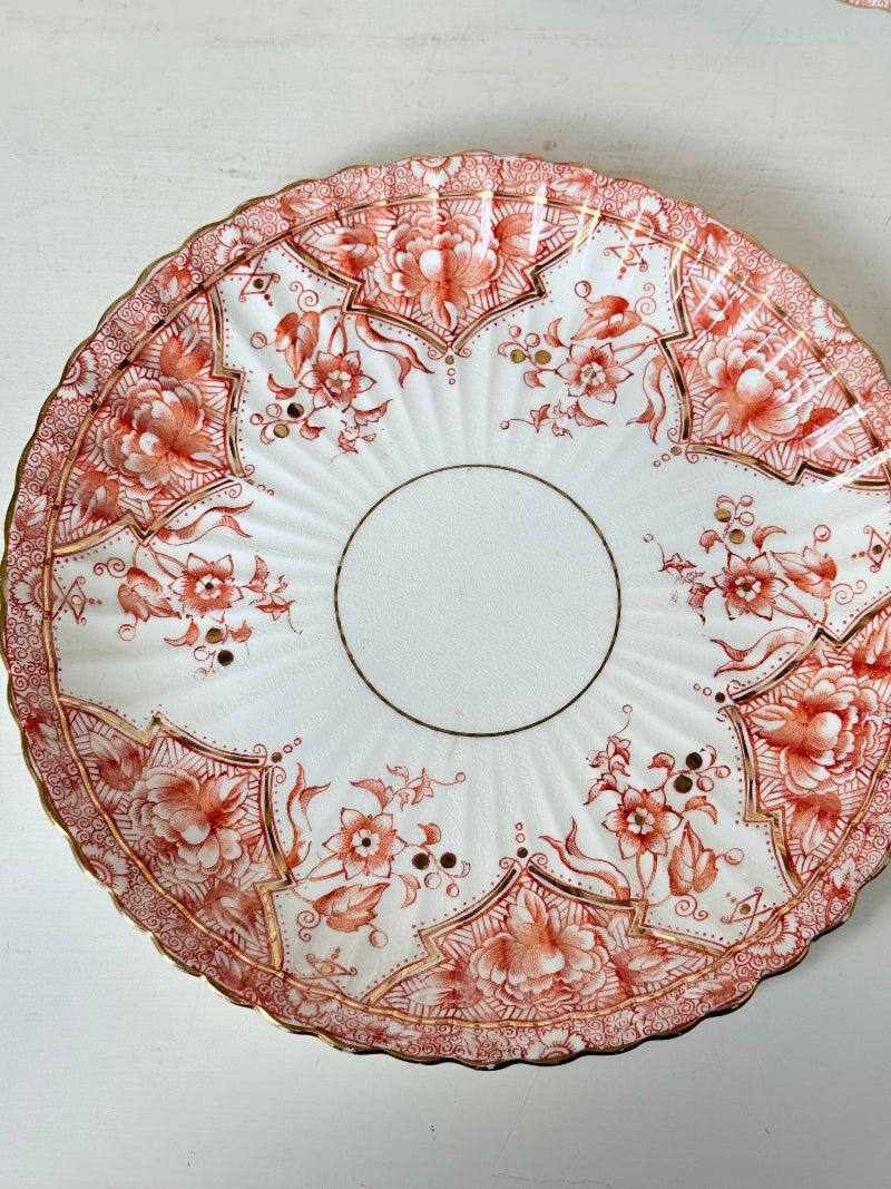 pair of vintage porcelain coral transfer plates with scalloped edges and gilt detail on white surface