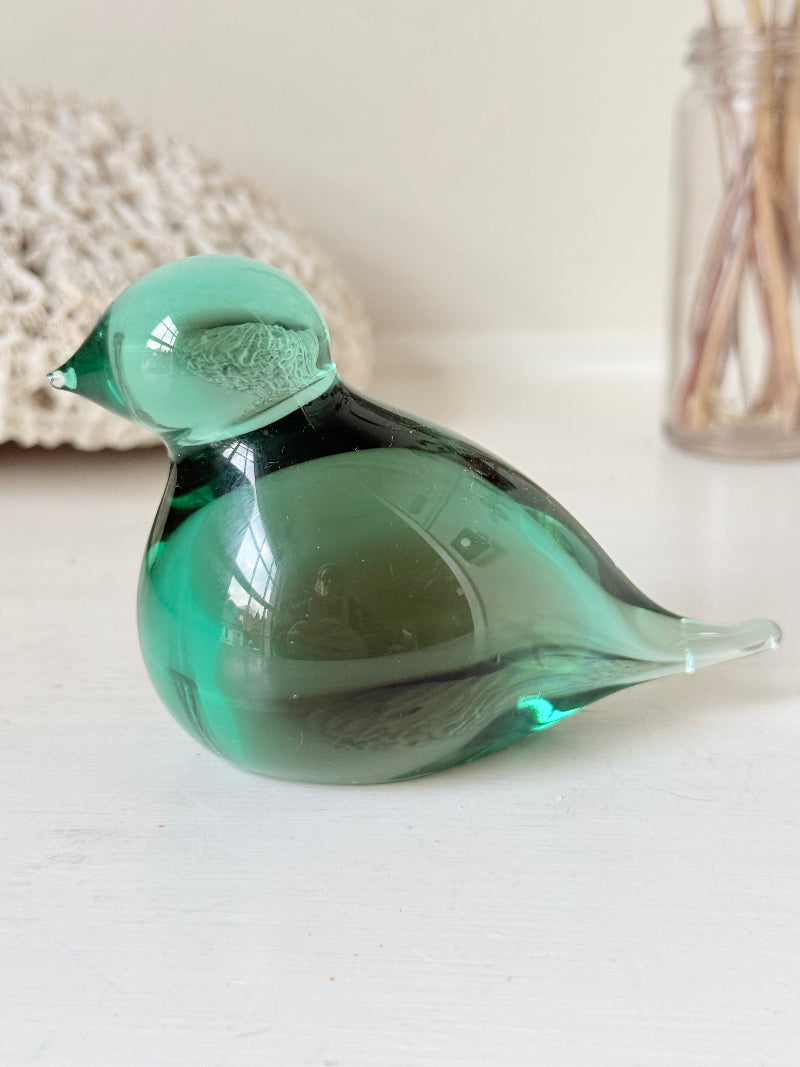 Vintage green glass bird paperweight photographed on a white surface
