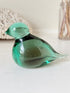 Vintage green glass bird paperweight photographed on a white surface
