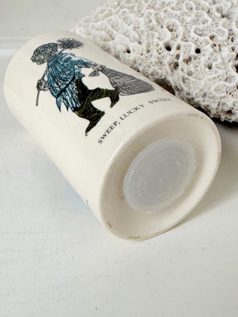 Vintage ceramic money box with illustrated figures photographed on a white surface