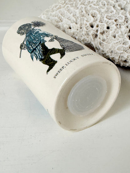 Vintage ceramic money box with illustrated figures photographed on a white surface