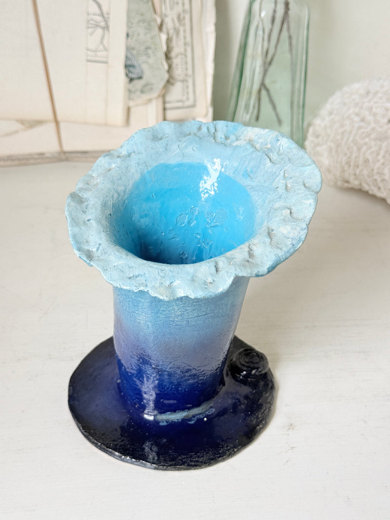 Handmade studio pottery trumpet vase in ombre blue with a frilled rim, photographed on a white surface